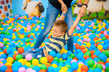 Fototapeta na wymiar A boy with mother in the playing room with many little colored balls