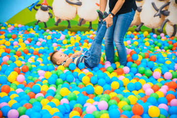 Fototapeta na wymiar A boy with mother in the playing room with many little colored balls