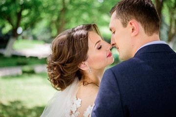 Fototapeta premium A moment before a kiss of groom and bride in the park