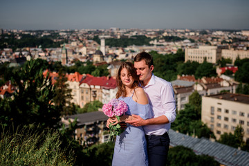 Fototapeta premium Man hugs woman tender standing before beautiful cityscape