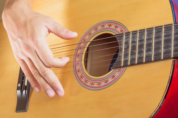 young male playing on acoustic classical guitar, close up