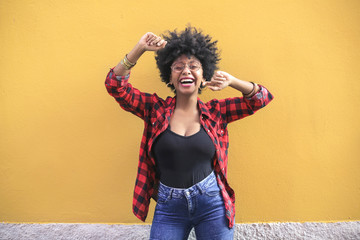 Euphoric girl dancing in front of a yellow wall