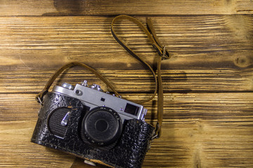 Retro photo camera in leather case on wooden background