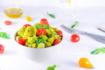 Salad Bowl with cherry tomatoes, boiled broccoli, basil and fresh ingredients on the white wooden background. Healthy lifestyle concept. Detox, diet, vegitarian. Selective focus. Space for text.