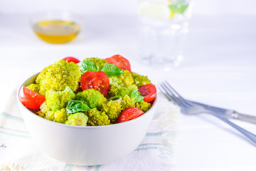 Salad Bowl with cherry tomatoes, boiled broccoli, basil and fresh ingredients on the white wooden background. Healthy lifestyle concept. Detox, diet, vegitarian. Selective focus. Space for text.