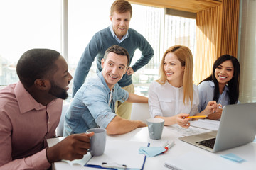 Delighted bearded blonde man standing behind his partners