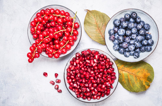 Purple and red color fruits in bowls  top view.Berries, pomegranate, redcurrant winter fruits healthy snack.