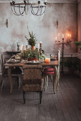 Christmas table setting. Vintage chairs, natural pine tree branches, candles. Rural or rustic style decorations