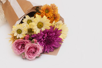 Bouquet of autumn chrysanthemum flowers in brown paper on white background