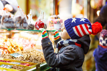 Obraz na płótnie Canvas Little kid boy with gingerbread and sweets stand on Christmas market