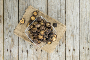 Portion of Shiitake mushrooms (dried) on wooden background, selective focus