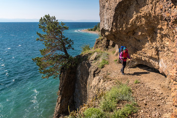 A tourist walks along a dangerous path over a cliff