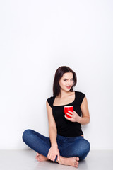 Young woman sitting at home floor with coffee cup