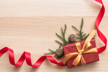 Christmas gift box present on wooden table background with xmas pine conifer and leaves for boxing day winter holiday ornament decoration
