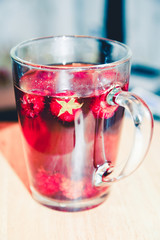 Raspberry tea. Red fruit tea, hot energy drink in glass mug. Teatime, pastime, cozy atmosphere in home, cafe, cafeteria in cold weather. 5 o'clock. Traditional black tea with herbs and berries.