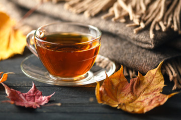 Autumn, fall leaves, hot cup of coffee and a warm scarf on wooden table background. Seasonal, morning coffee, sunday relax and still life concept.