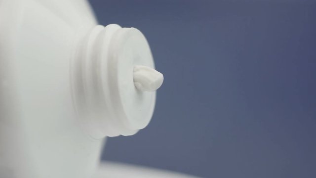 Moisturizing white cream squeezed out of the tube on a purple background. White glue for repair