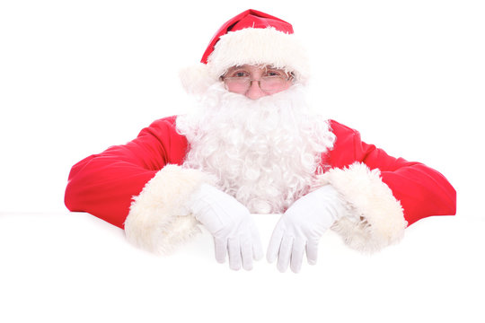 Kind Santa Claus looking out from behind the blank sign isolated on white background with copy space