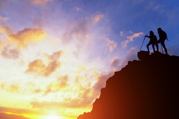 Asia couple hiking help each other silhouette in mountains with sunlight.