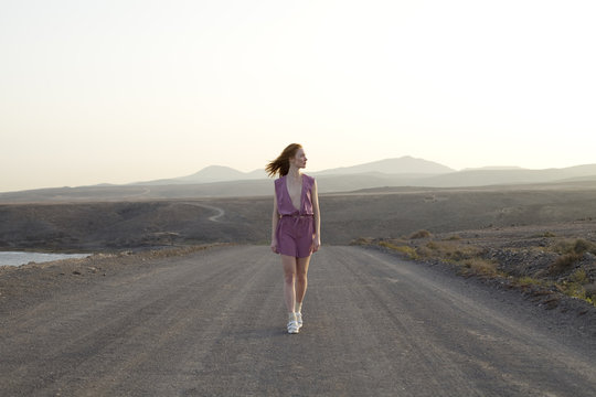 young woman walking down road in deserted landscape