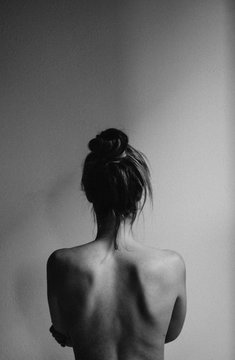 young woman with bare back towards camera intimate studio black and white