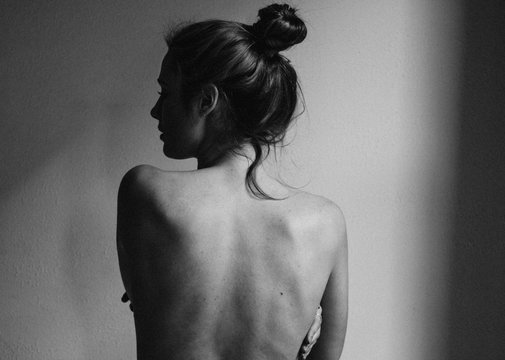 young woman with bare back towards camera intimate studio black and white