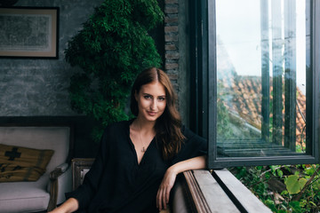Portrait of smiling woman sitting next to window