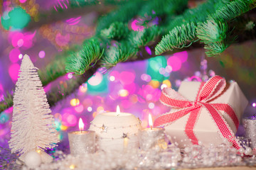 Christmas card. Background on a theme of New Year's  party. Decorated fir-tree with gifts and candles on the background of colorful festive lights. A magical evening.