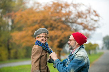 Father and son playing in the park in autumn scenery