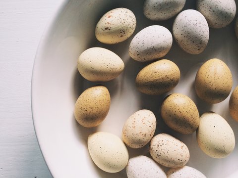 A group of brown and white speckled easter eggs in a white bowl