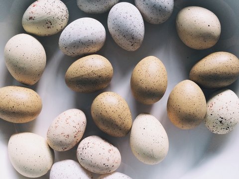 A group of brown and white speckled easter eggs in a white bowl