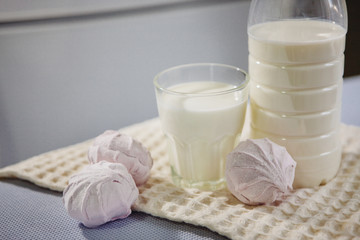 Glass and bottle of milk and pink zefir (Russian marshmallow) on the table
