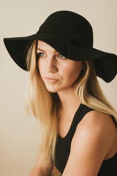 Young model in black floppy hat posing for fashion shoot in black crop top