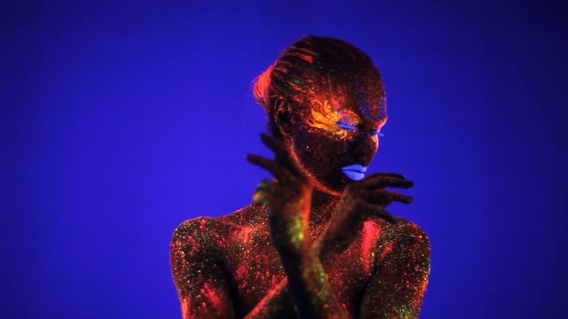 Portrait of beautiful girl with ultraviolet paint in color light