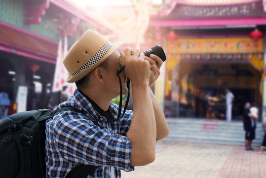 Tourist sightseeing old town, travel concept.Street photographer taking a picture of old shrine chinese temple in phuket old town with vintage camera ,side view.