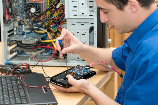 Young technician working on broken computer in his office
