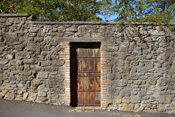 Fototapeta na wymiar Puerta oxidada y muro de piedra, Volterra.