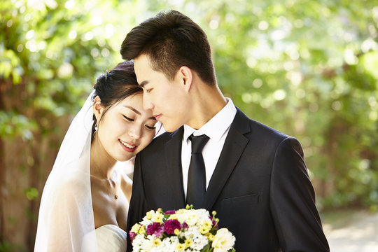 outdoor portrait of a happy and loving asian newly-wed couple