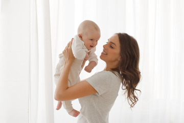 Mom holds a baby in the arms window background