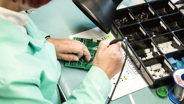Woman holding pincette and soldering iron install electronic components on PCB (Printed circuit boards) 4K TIMELAPSE