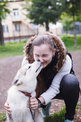 Portrait of beautiful young woman with husky dog that licks her face