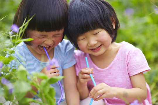 close up of two happy little girls drinking water outdoor