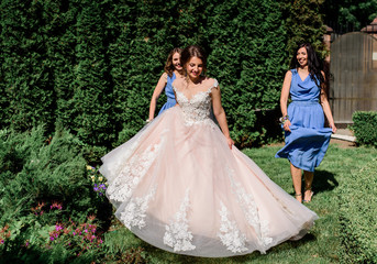 Fototapeta premium Bride and bridesmaids in blue dresses walk in a green garden