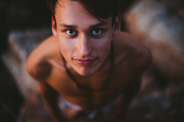 Close up shot of a young beautiful man on the rock from above