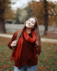 Portrait of a beautiful very cute girl with long straight hair, which flutter in the wind ; knitted sweater in autumn