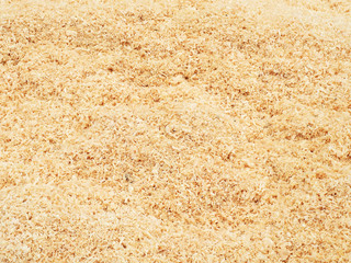 Texture of natural wood chips, the surface of a heap of fresh sawdust of a non-uniform beige color. Logging, lumber, timber and carpentry waste