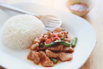 fried pork with thai curry and rice on wood background , Thai food