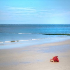 Roter Liegestuhl am einsamen Strand