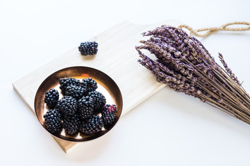 Fototapeta na wymiar Ripe blackberries in a copper bowl and lavender branch