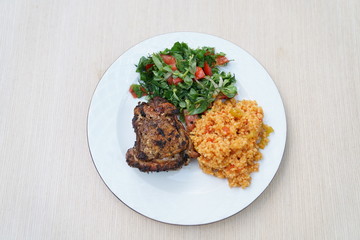 food plate consisting of bulgur, salad and meat.